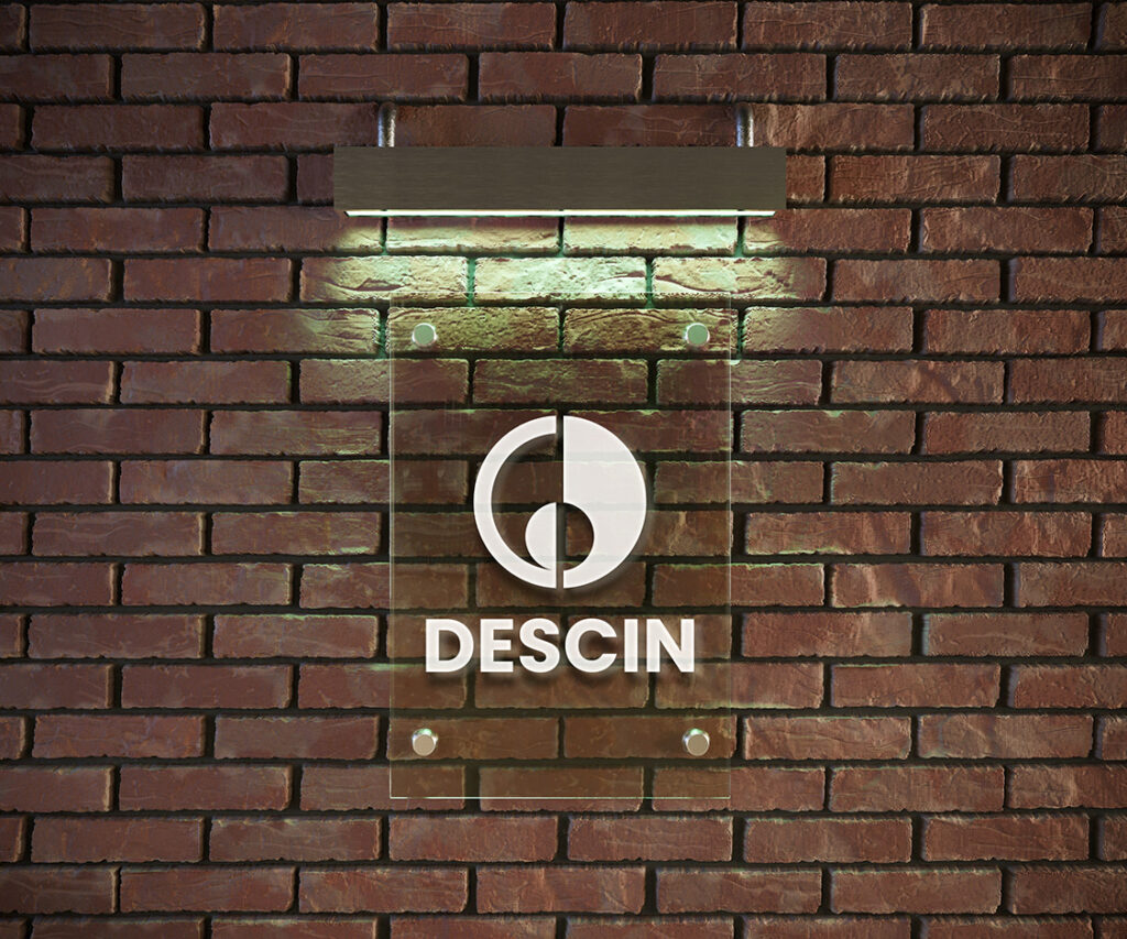 DESCIN signage mockup on an acrylic sheet in front of a bricked wall