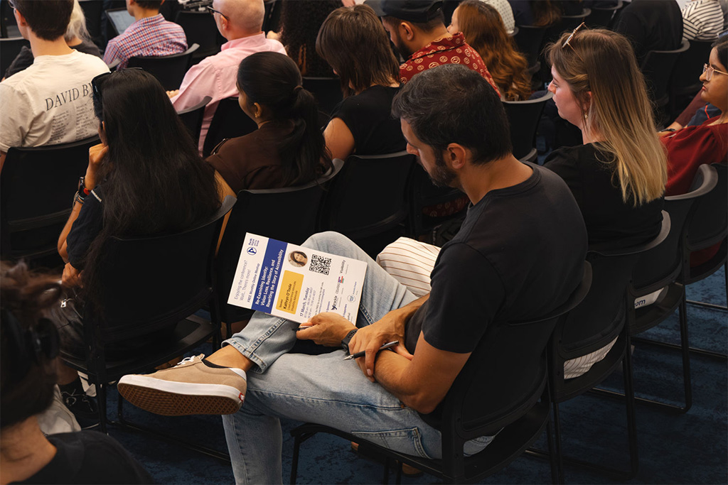A conference attendee reading the printed poster of the upcoming free monthly online meetup